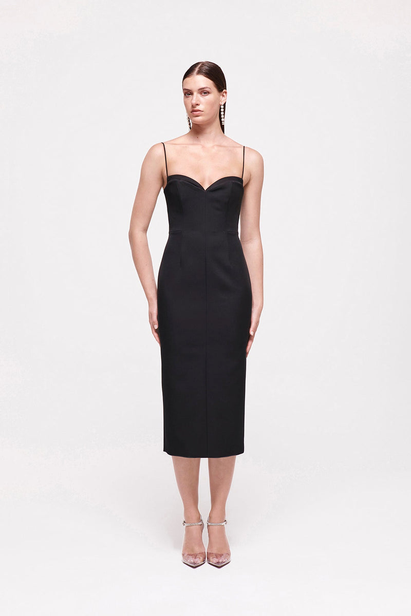 Front on image of model wearing the Bodie Dress in Black which features a sweetheart neckline and thin strap falling to a mid length silhouette.
